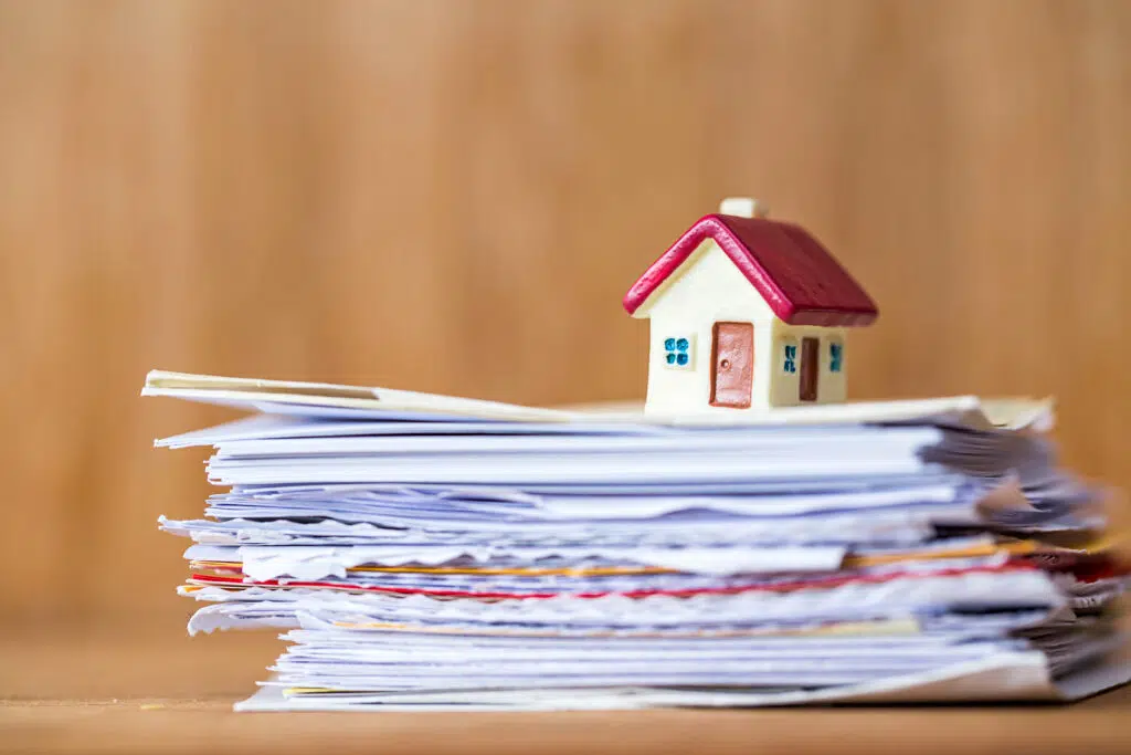 miniature house with red roof on stack of paper