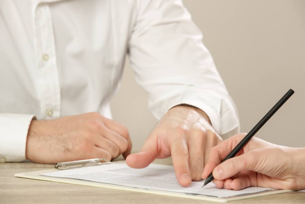 Businessman pointing finger at the document and showing to the customer where to sign a contract